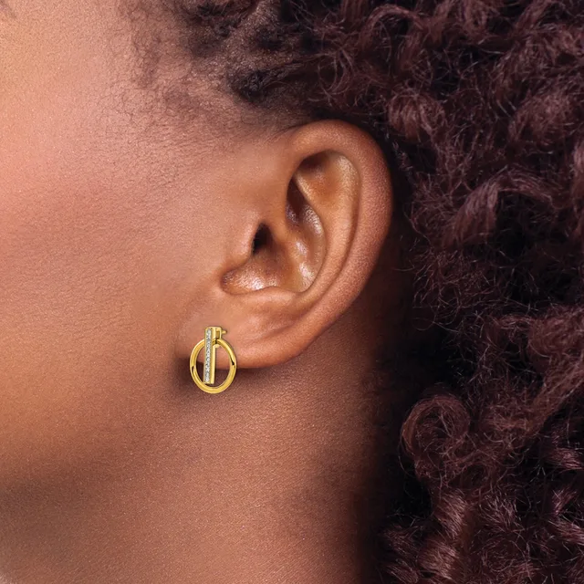 A close-up side view of a person's ear wearing a small gold hoop earring with a textured or diamond-cut surface detail.