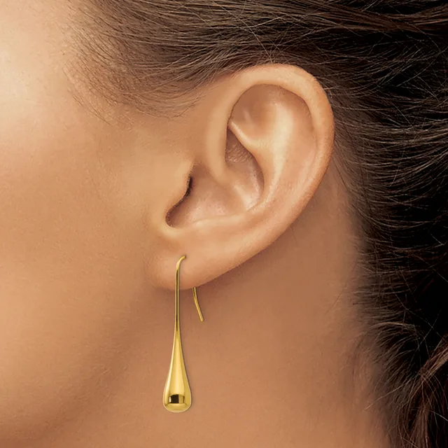 A person wearing a gold teardrop-shaped dangle earring on a threader post, shown in profile view against their ear.