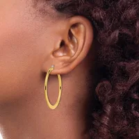 A person wearing a pair of gold hoop earrings, shown from the side profile with curly dark hair visible.