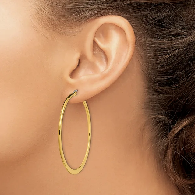 A woman wearing large oval gold hoop earrings, shown in profile from the side of her face and ear.
