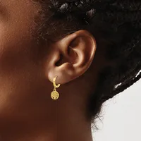 A person wearing a gold hoop earring with a small circular pendant featuring a tree design hangs from the lobe.