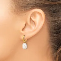 A person wearing a gold-toned hoop earring with a white pearl pendant hanging from the lobe.