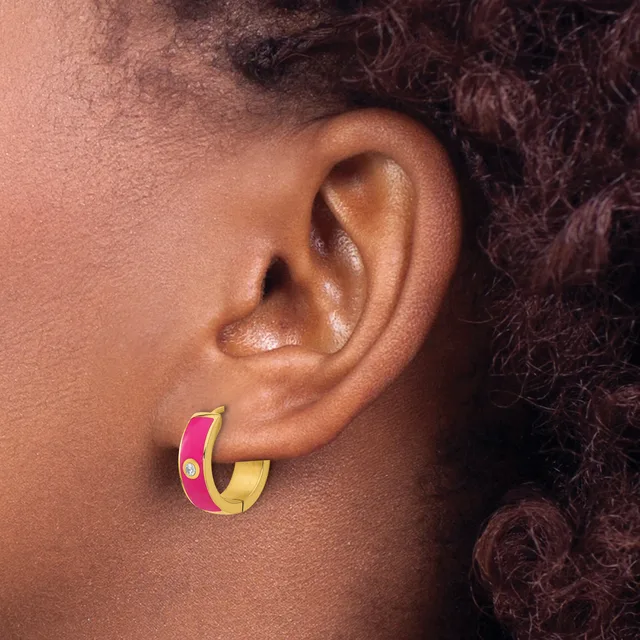 A person wearing a gold and hot pink enameled hoop earring with a small circular stone detail, shown from the side profile.