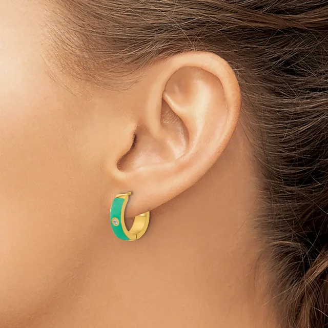 A person wearing small hoop earrings with green and gold coloring and a small rhinestone detail, shown from the side view of their ear.