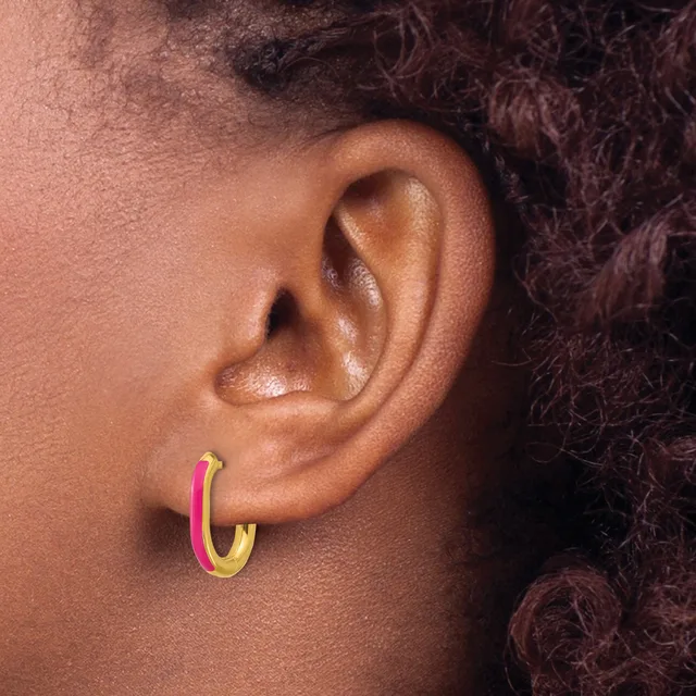 A person wearing a pink and gold hoop earring in their earlobe, shown in profile view.