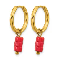 A pair of gold-colored hoop earrings with red cylindrical bead charms hanging from the bottom of each hoop.