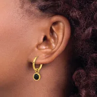 A person wearing a gold hoop earring with a small black onyx stone pendant hanging from it.
