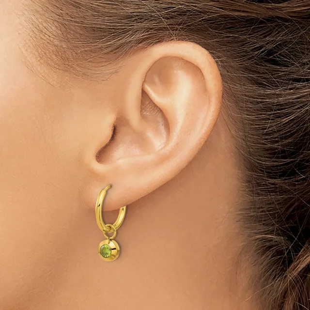 A woman wearing a gold hoop earring with a small dangling sphere, shown from the side view of her ear and neck.