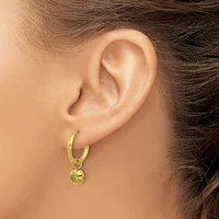 A woman wearing a gold hoop earring with a small dangling sphere, shown from the side view of her ear and neck.