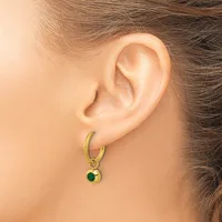 A person wearing a gold hoop earring with a small round green stone charm hanging from it.