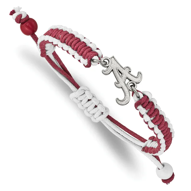 A bracelet with burgundy and white woven cord sections, silver-toned metal spacers, a decorative ornamental charm, and small beads at the ends.