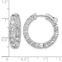 A pair of silver hoop earrings set with round diamonds, displayed next to a ruler showing their approximate 1-inch diameter size.