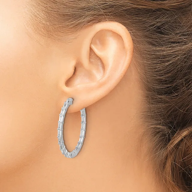 A woman wearing a textured silver hoop earring visible from the side profile, with her ear and part of her hair shown against a neutral background.