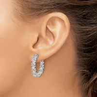 A U-shaped hoop earring set with small round diamonds in a pave setting, worn on a person's ear.