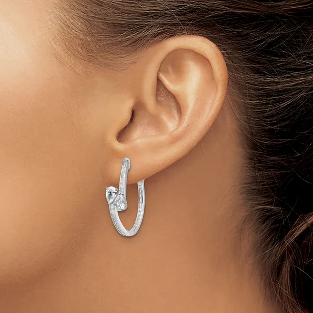 A woman wearing a textured silver hoop earring with a decorative knot detail, shown from the side profile near her ear.