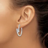A woman wearing a textured silver hoop earring with a decorative knot detail, shown from the side profile near her ear.