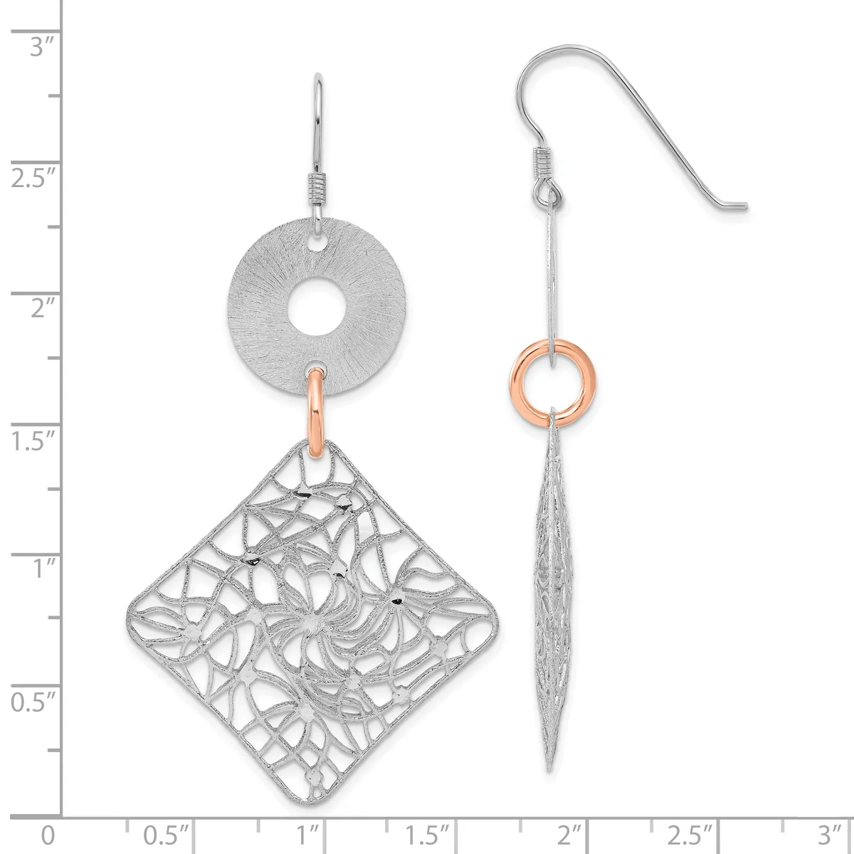 Two silver dangle earrings with fish hook backs, one featuring a circular disc with a textured diamond-shaped filigree pendant, the other a long tapered spike with a small copper ring, displayed against a ruler showing measurements up to three inches.