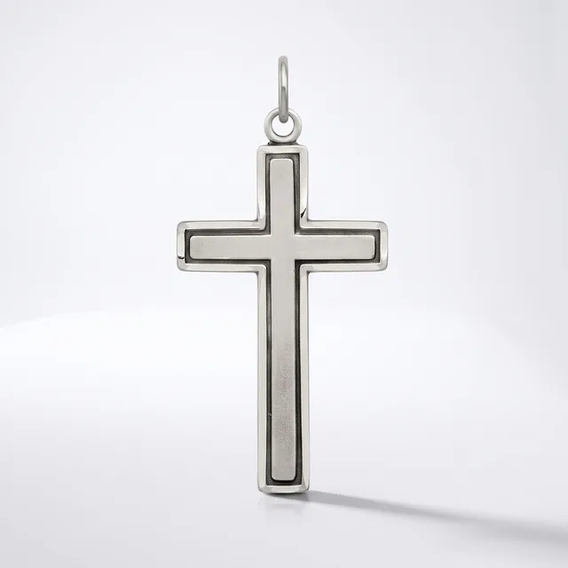 A silver cross pendant with a hollow rectangular center and rounded edges, suspended from a loop at the top, displayed against a white background.