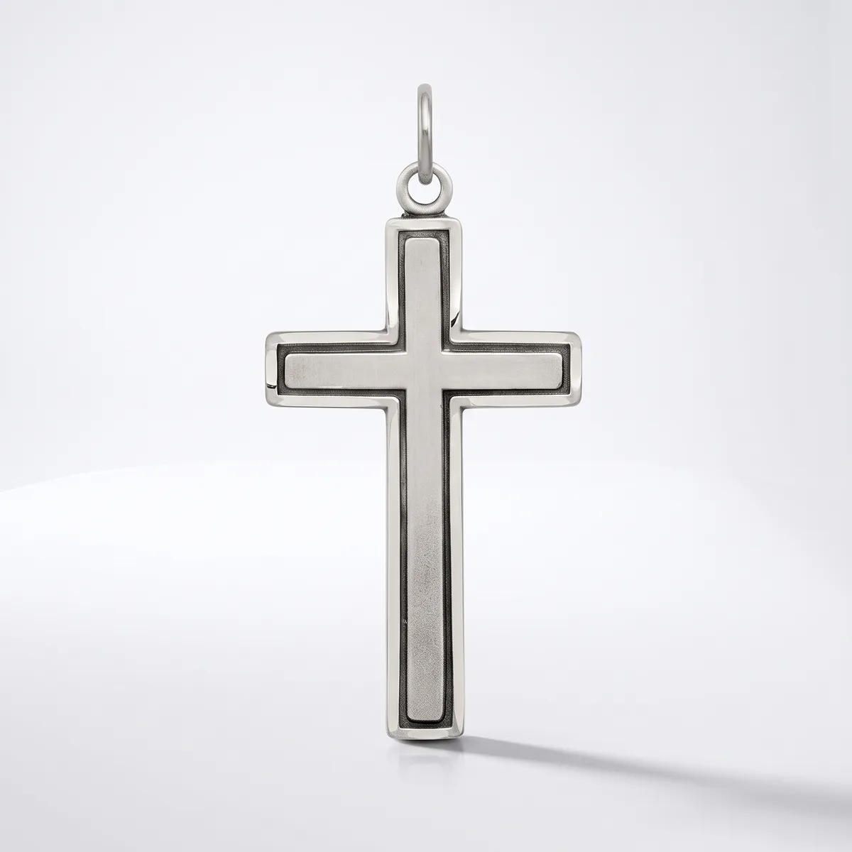 A silver cross pendant with a hollow rectangular center and rounded edges, suspended from a loop at the top, displayed against a white background.
