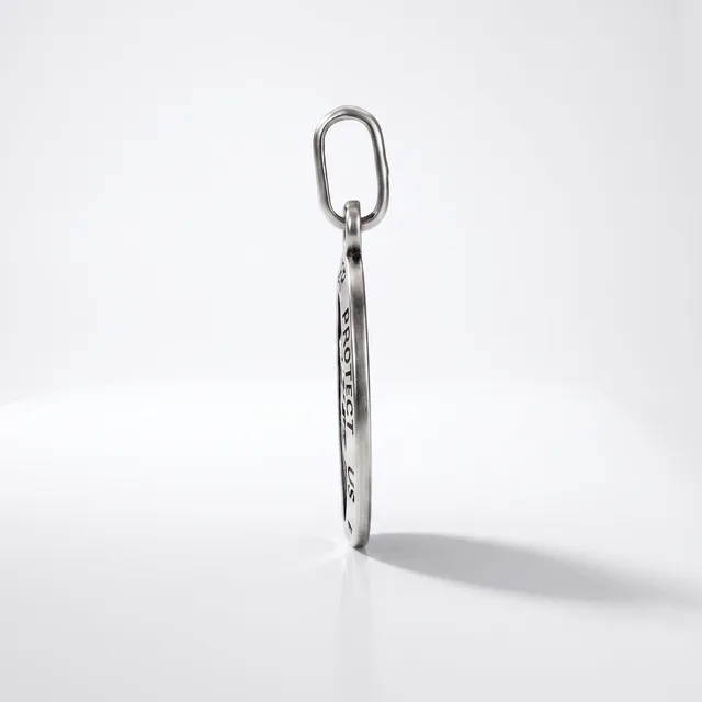 A silver elongated oval keychain with engraved text hangs from an oval metal ring against a white background.