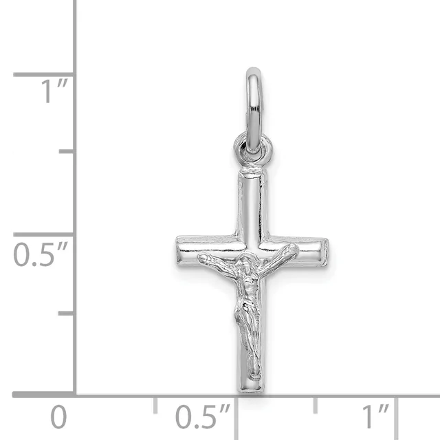 Silver crucifix pendant with corpus figure, shown against a ruler indicating approximately one inch in height.