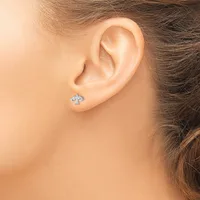 A person wearing a small cross-shaped stud earring with blue stones in their pierced earlobe.