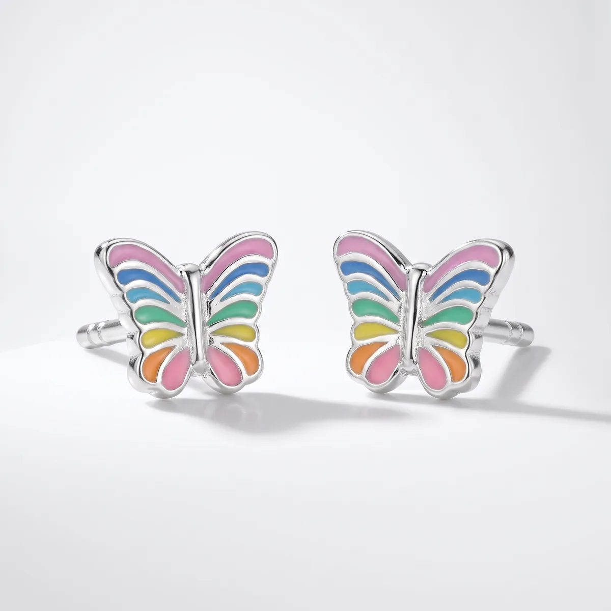 A pair of silver butterfly cufflinks with rainbow-colored enamel wings displayed on a white background.