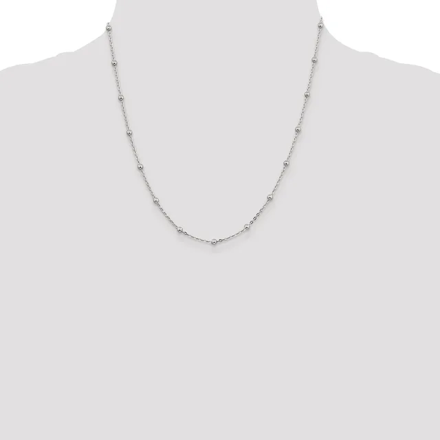 A delicate silver-toned chain necklace with small round beads evenly spaced along its length, displayed on a mannequin bust.
