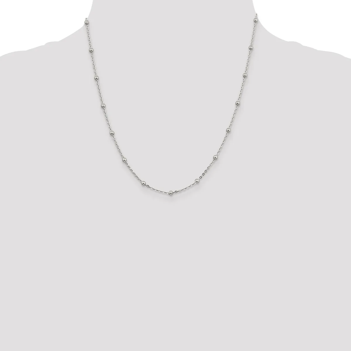A delicate silver-toned chain necklace with small round beads evenly spaced along its length, displayed on a mannequin bust.