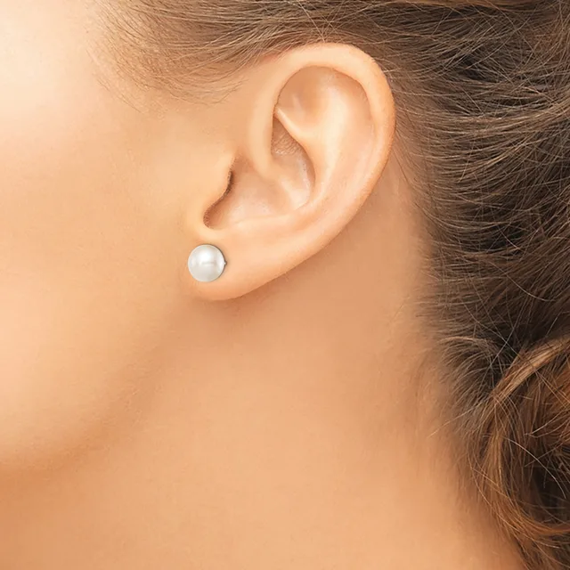 A person wearing a small round white pearl stud earring in their pierced earlobe, shown in profile against their bare shoulder.