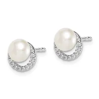 A pair of silver stud earrings, each featuring a round white pearl set above a curved crescent of small round diamonds.
