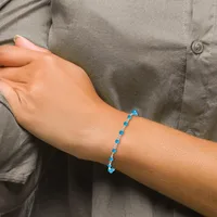 A person wearing a gray button-up shirt displays a blue beaded bracelet on their wrist, featuring alternating round blue stones and silver spacer beads.