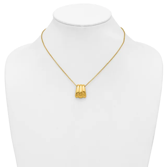 A gold-toned pendant necklace with a ridged cylindrical charm displayed on a white mannequin bust.