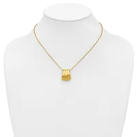 A gold-toned pendant necklace with a ridged cylindrical charm displayed on a white mannequin bust.