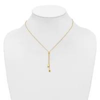 Gold-toned adjustable lariat necklace with small cube charms hanging from two delicate chains, displayed on a white mannequin bust.