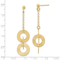 Gold-colored dangle earrings with brushed textured finish featuring two stacked circular rings suspended from a delicate chain, shown against a measurement scale.