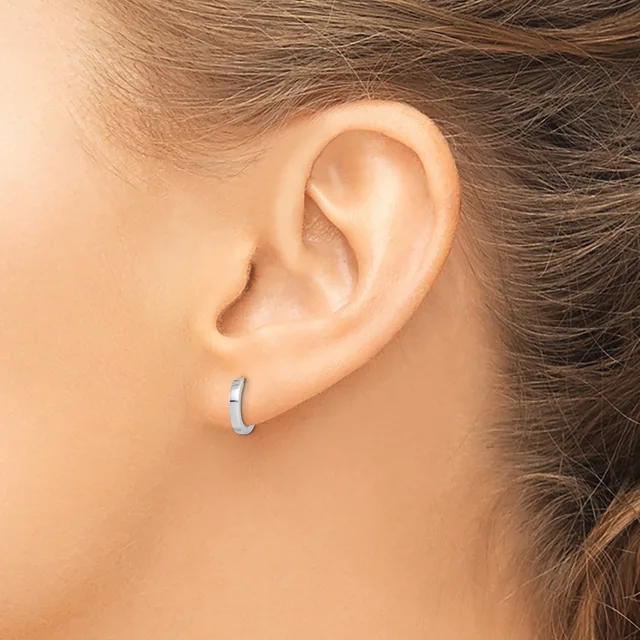 A person wearing a small silver hoop earring in their earlobe, shown in profile with brown hair pulled back.