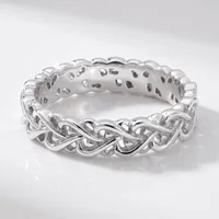 A silver braided twist band ring with an open weave design, photographed on a white reflective surface.