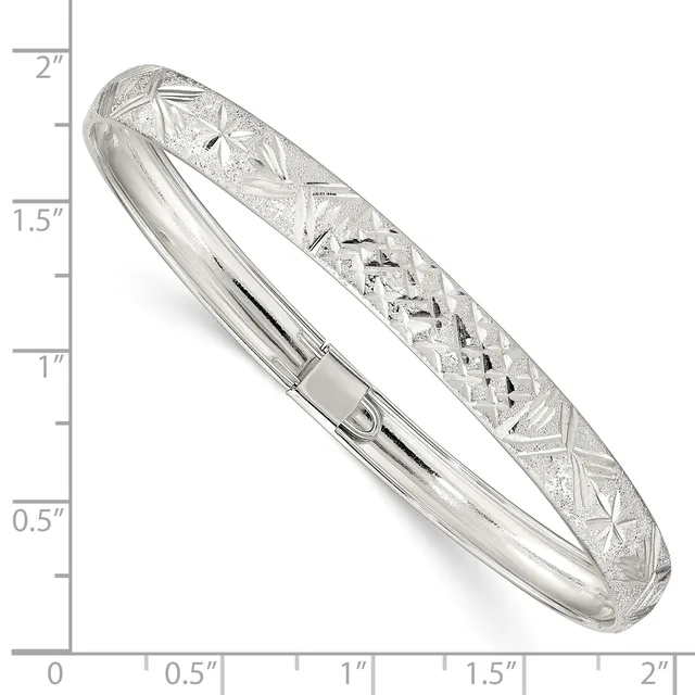 Silver bangle bracelet with textured geometric patterns on the upper half and polished finish on the lower half, shown next to a ruler measuring approximately two inches in width.