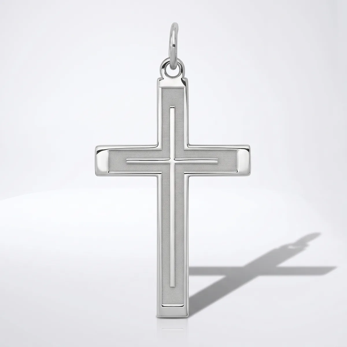 Silver cross pendant with a polished finish and beveled edges, shown against a white background with its shadow visible.