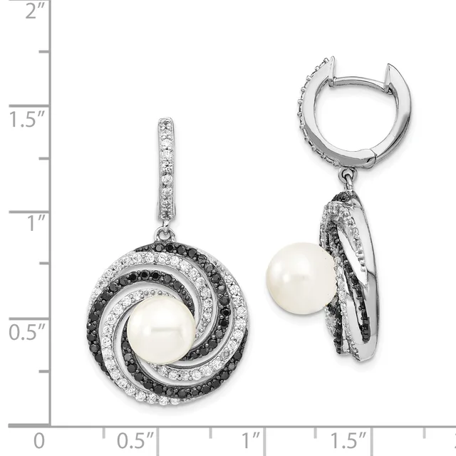 A pair of silver earrings with white pearls surrounded by concentric circular frames set with black and white diamonds, displayed next to a ruler showing approximately 1.5 inches in length.