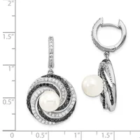 A pair of silver earrings with white pearls surrounded by concentric circular frames set with black and white diamonds, displayed next to a ruler showing approximately 1.5 inches in length.