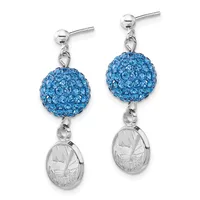 A pair of silver stud earrings with blue crystal-encrusted spheres suspended above small oval medallions featuring an engraved landscape scene.
