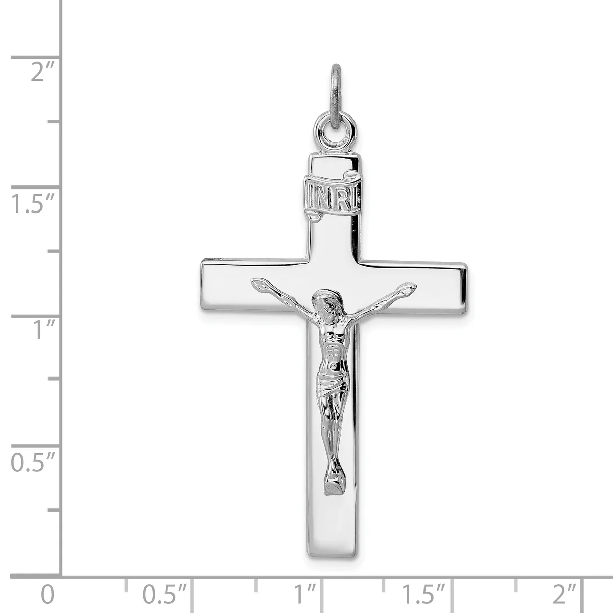 A silver crucifix pendant with a polished cross and detailed corpus figure, shown against a ruler measuring approximately 2 inches in height.