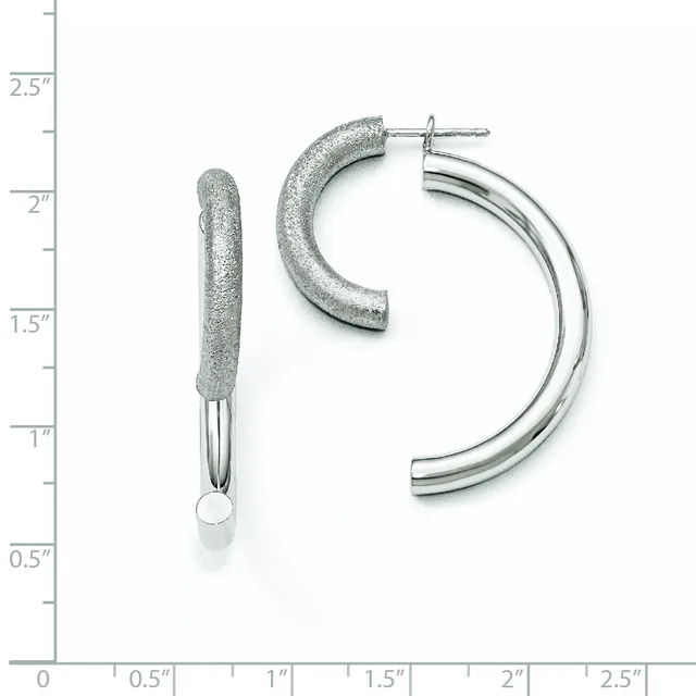 Two silver hoop earrings displayed against a ruler showing measurements up to 2.5 inches: one textured curved post earring and one polished chunky hoop with post back.
