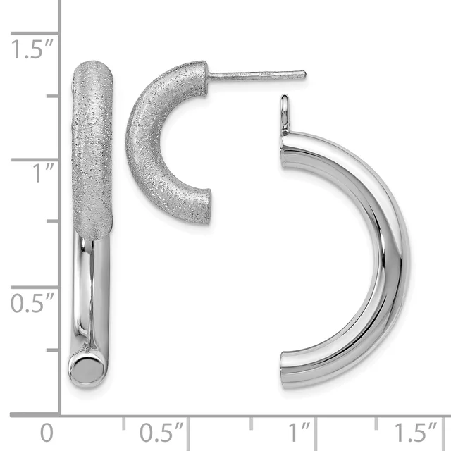 Three silver earrings displayed against a measurement scale: a textured cylindrical stud, a curved textured hoop, and a polished curved hoop.