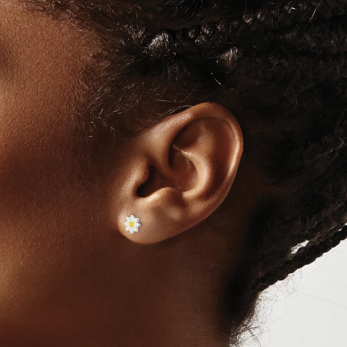 A person wearing a small white daisy flower stud earring in their earlobe, shown in profile against a neutral background.