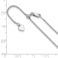 Silver bracelet with a curb chain and a small heart charm, displayed against a ruler showing measurements up to 2 inches.
