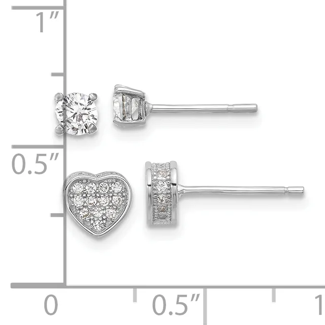 Two pairs of silver stud earrings displayed on a measurement scale: round diamond solitaires on top and heart-shaped diamond cluster earrings below.