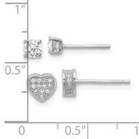 Two pairs of silver stud earrings displayed on a measurement scale: round diamond solitaires on top and heart-shaped diamond cluster earrings below.